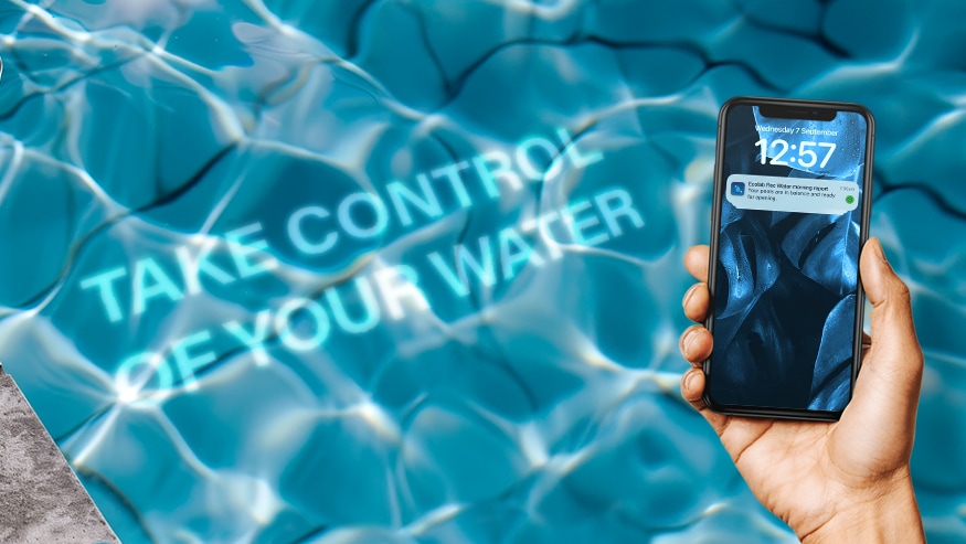 A hand holding a smartphone displaying a notification. In the background, there is an image of a swimming pool water with text overlaying it that reads take control of your water.