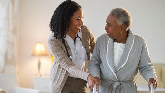 A long term care aid assisting an elderly woman.